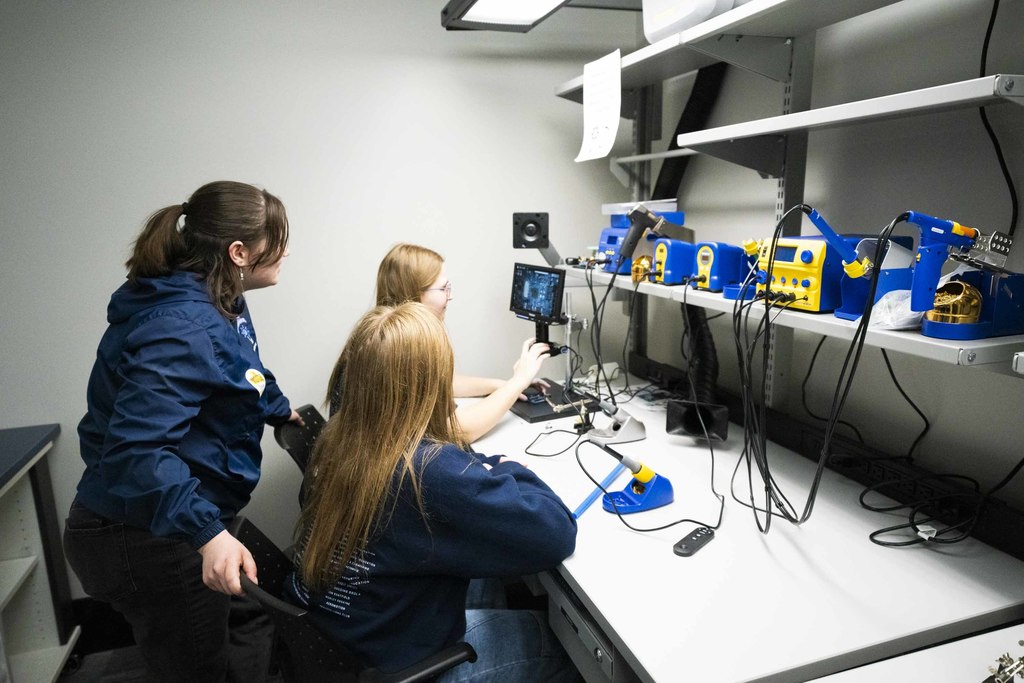 Three Hemlock students use a digital microscope to observe a microchip in the electronics lab at the KEEL Innovation Center