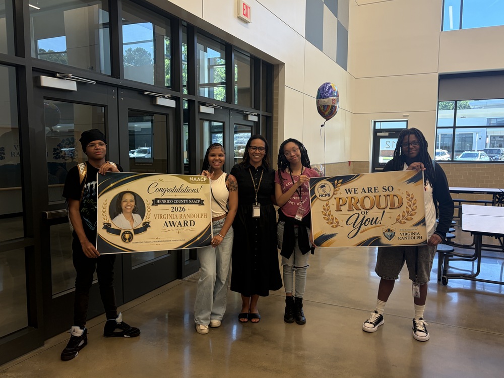 Principal Mayo posing with students holding  Congratulations banners