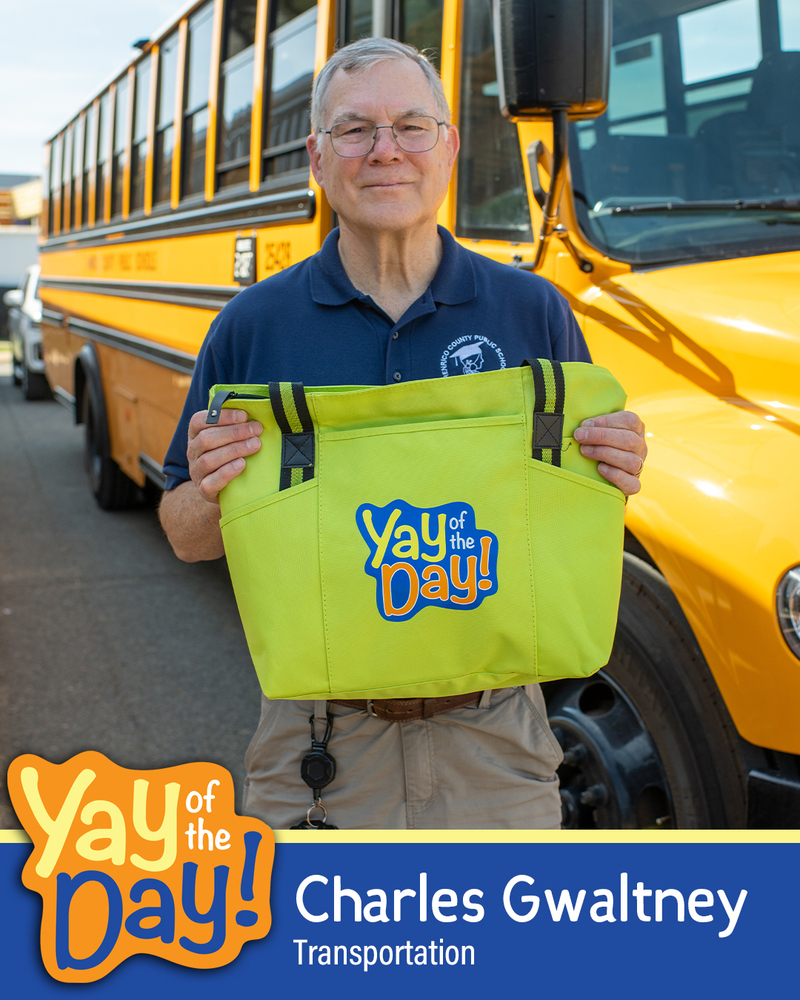 Charles Gwaltney of Transportation holds up a Yay of the Day bag in front of an HCPS school bus.