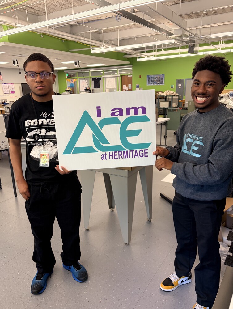 graphics students hold up a freshly printed yard sign