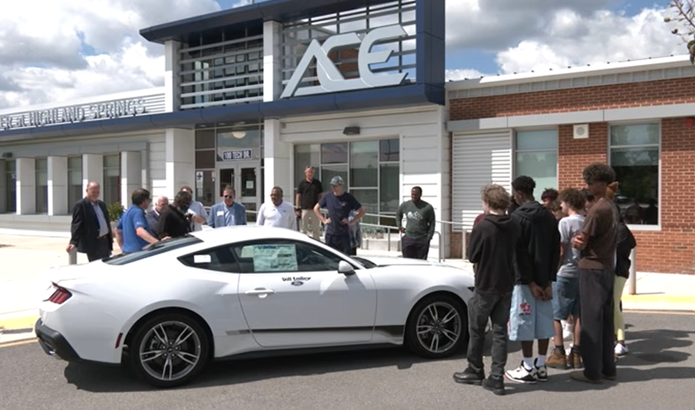 Bill Talley Ford Presents 2025 Ford Mustang to Automotive Technolgy Program at ACE Center at Highland Springs. Students are standing around Mustang with Teacher, Principal and Bill Talley Associates in front of ACE Center.