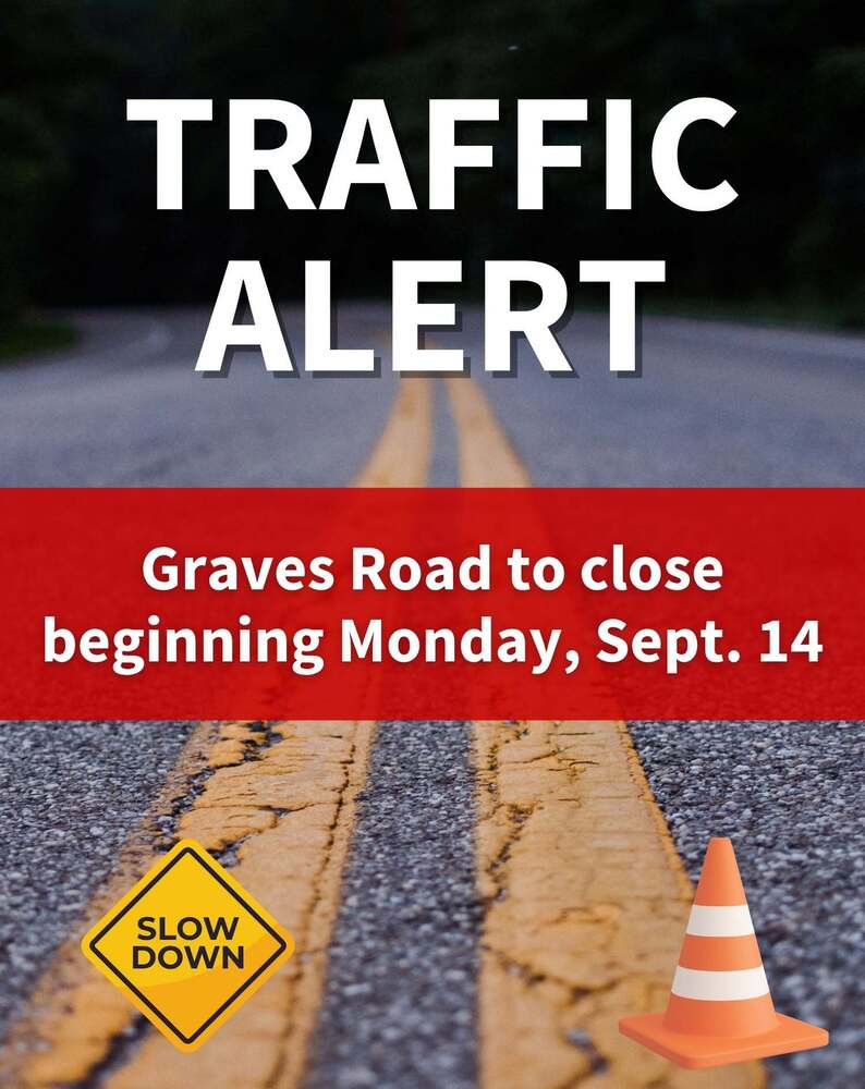 Road with orange cone and "Slow Down" yellow sign. Text reads TRAFFIC ALERT Graves Road to close beginning Monday, Sept 14