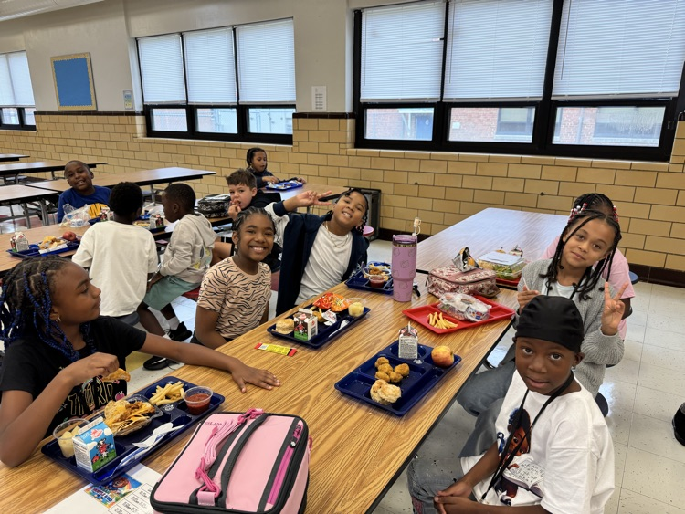 students smile at a cafeteria table 