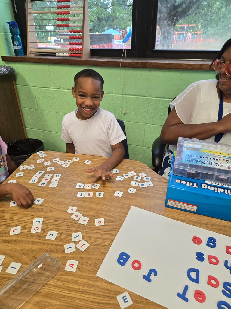 Students smiles as he shows off the words that he made.