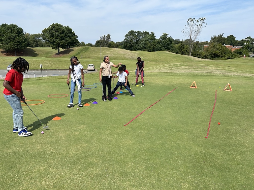 5th grade students stand on a golfing green.