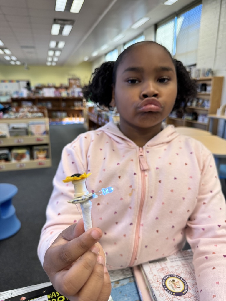 Students holds a light with a sunflower on top.