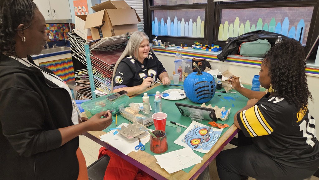 Staff sitting together to paint a pumpkin.