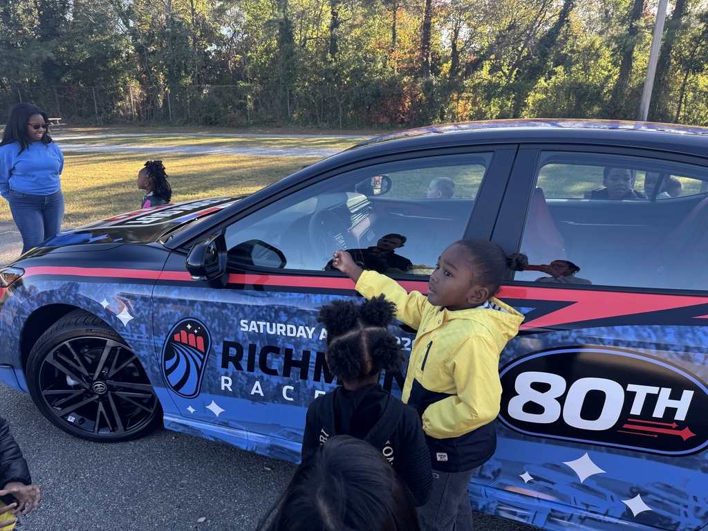 Sudent points to the race car as they ask questions.