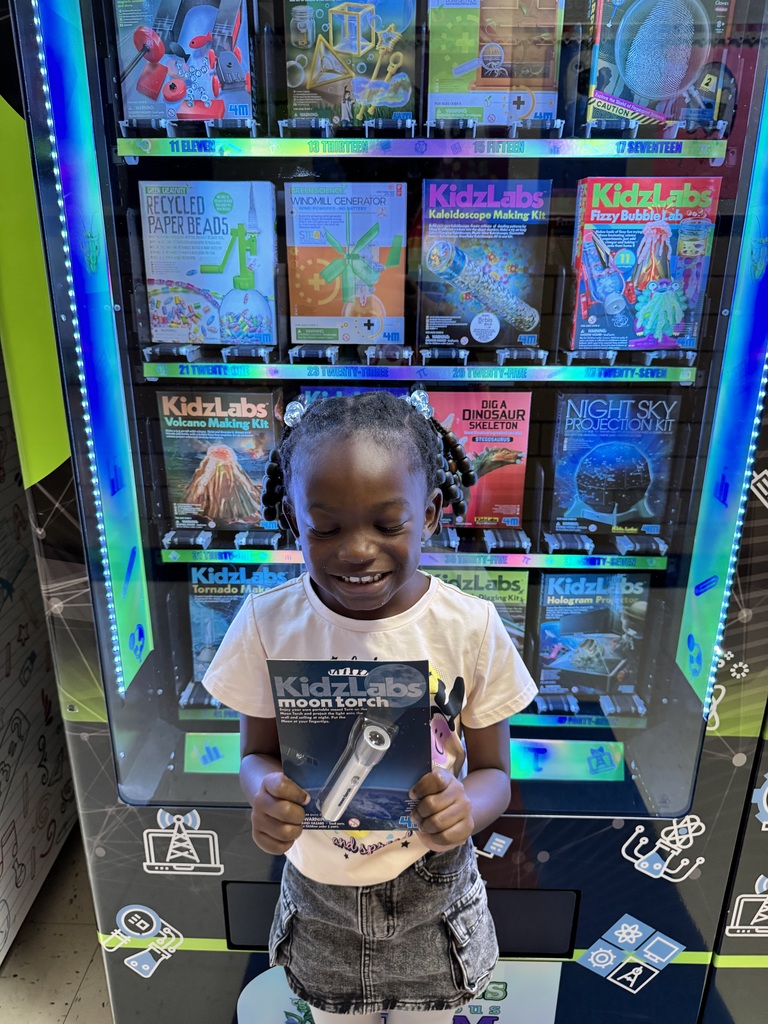 1st grade student holds up a flashlight that she selected.