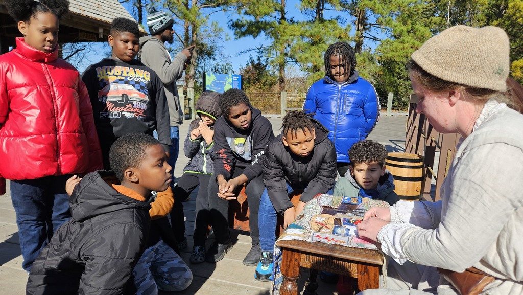 Students listen as she shows off how to quilt.