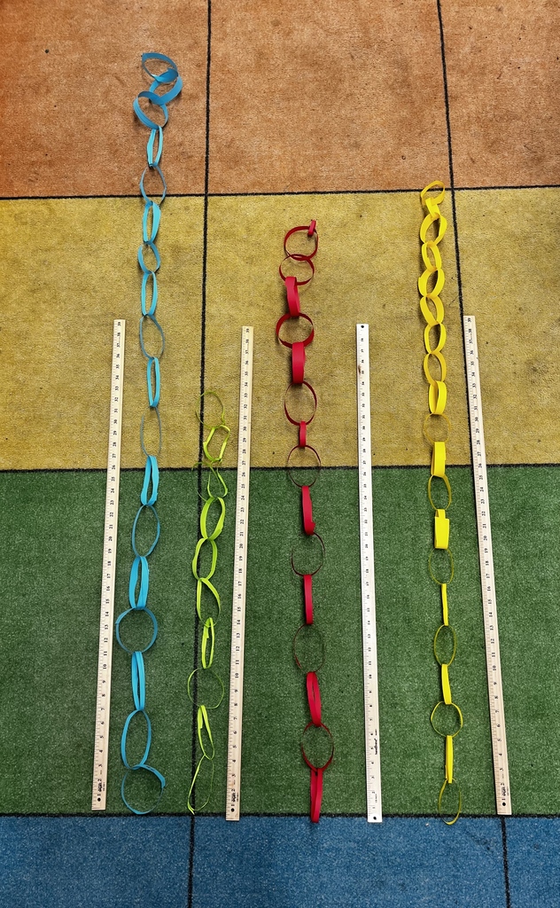 Student measure paper chains with yardsticks.