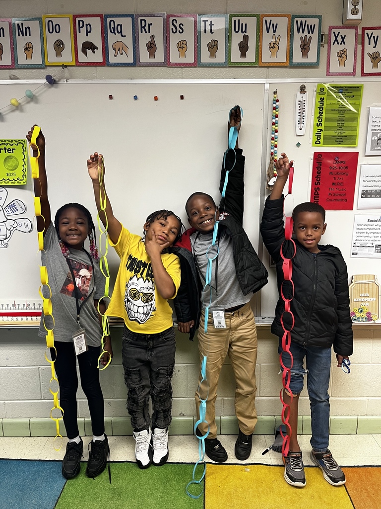 Students hold up paper chains they created and measured.