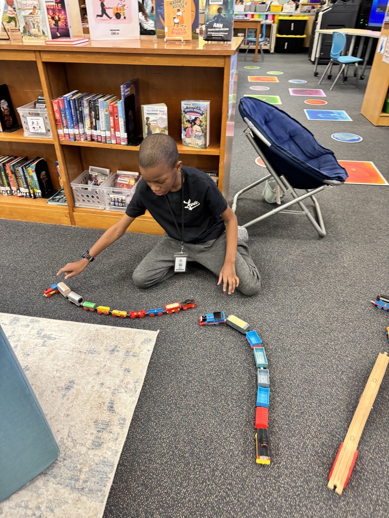 Student builds 2 trains to drive around the library.
