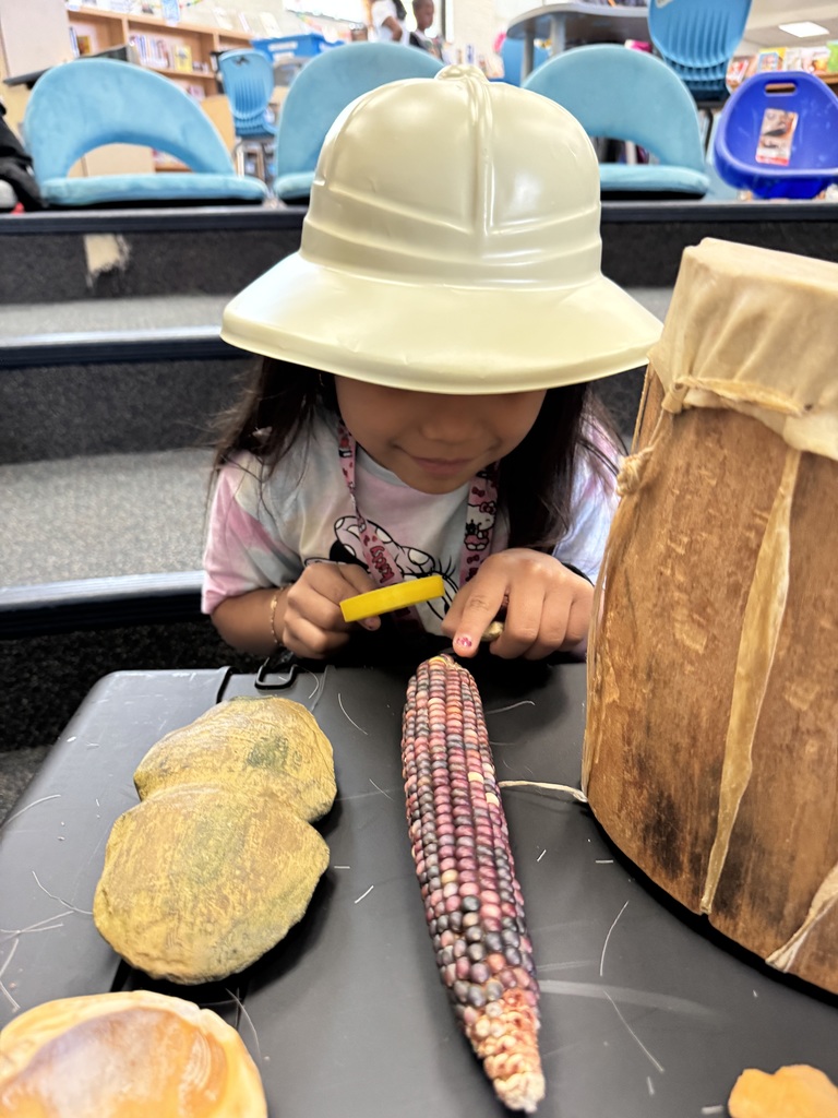A student uses a magnifying glass to examine a piece of corn.