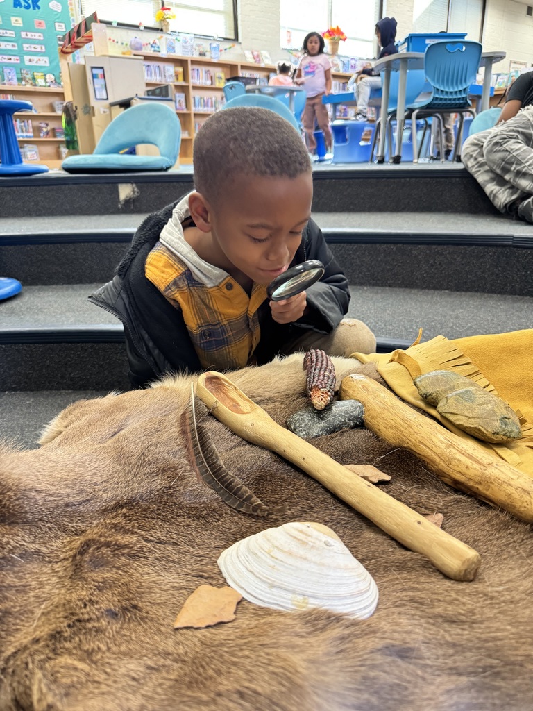 Students examine different artifacts with a magnifying glass.