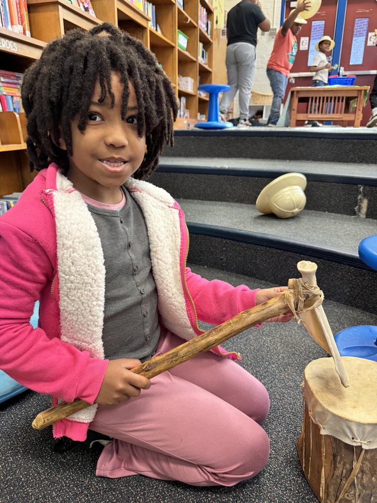Student holds a tool while looking at a drum.