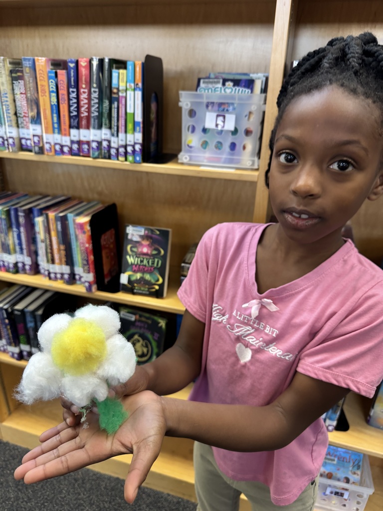 Student shows a flower made of pom poms.