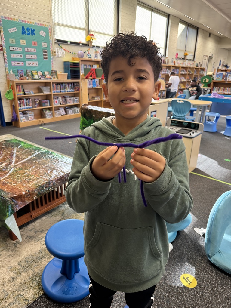 A student shows a dinosaur that he made out of pipe cleaners.