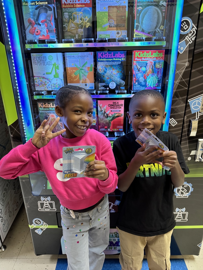 Two students show off the prisms that they selected from the STEAM machine.