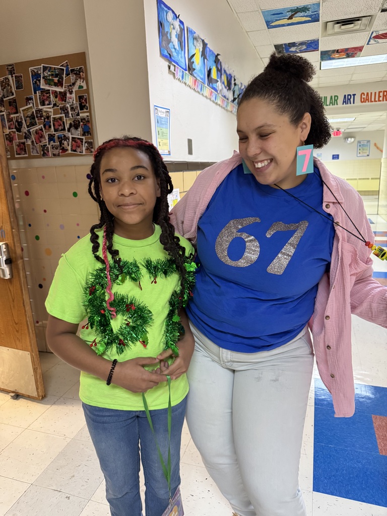 A student and teacher show off their shirts.