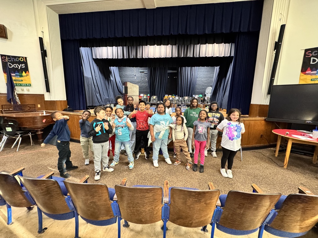 Group of spelling bee winners stand in front of the stage. 