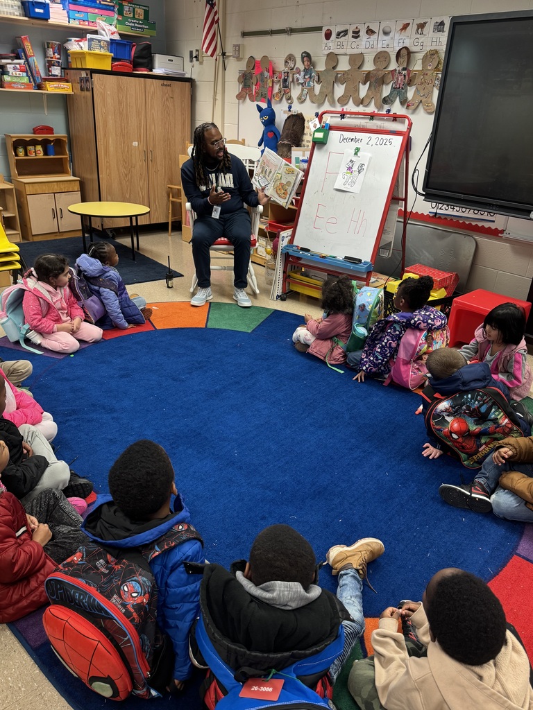 Principal Gordon reads aloud to the pre-k students on the carpet.