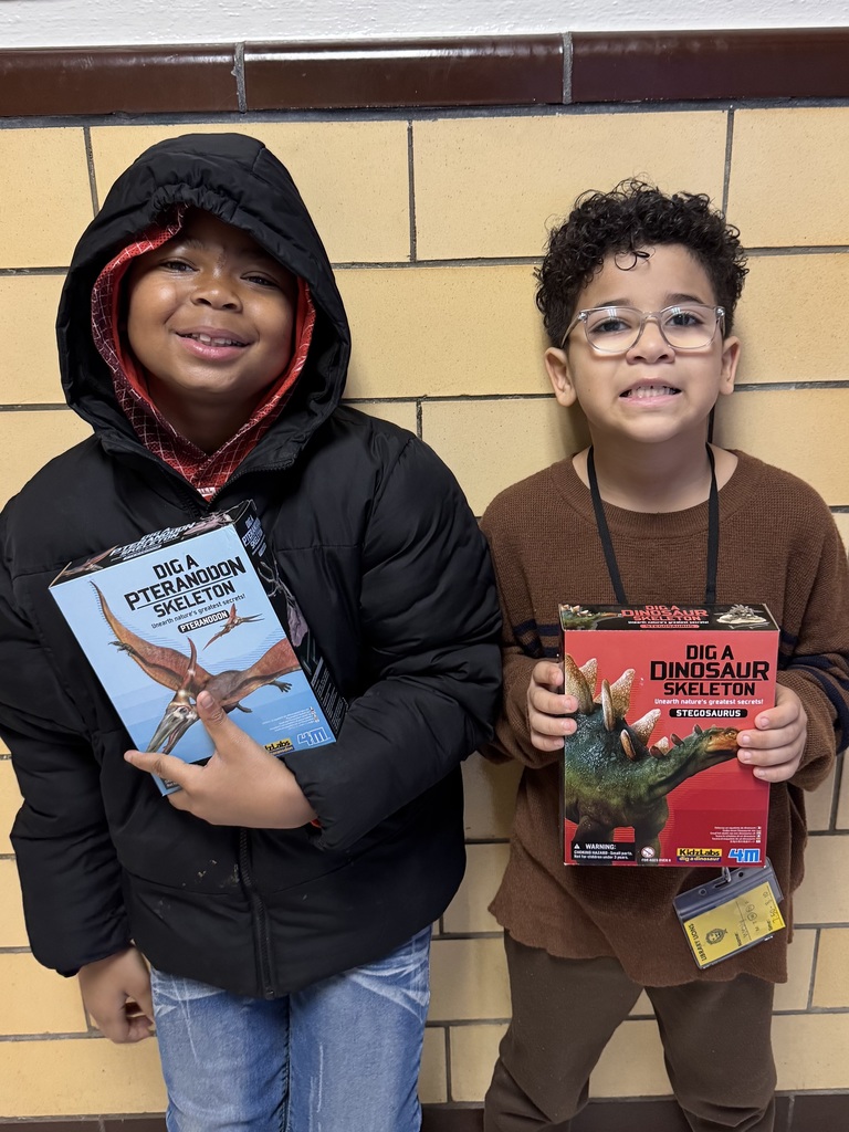 Fourth graders hold up dinosaur digging kits they selected.