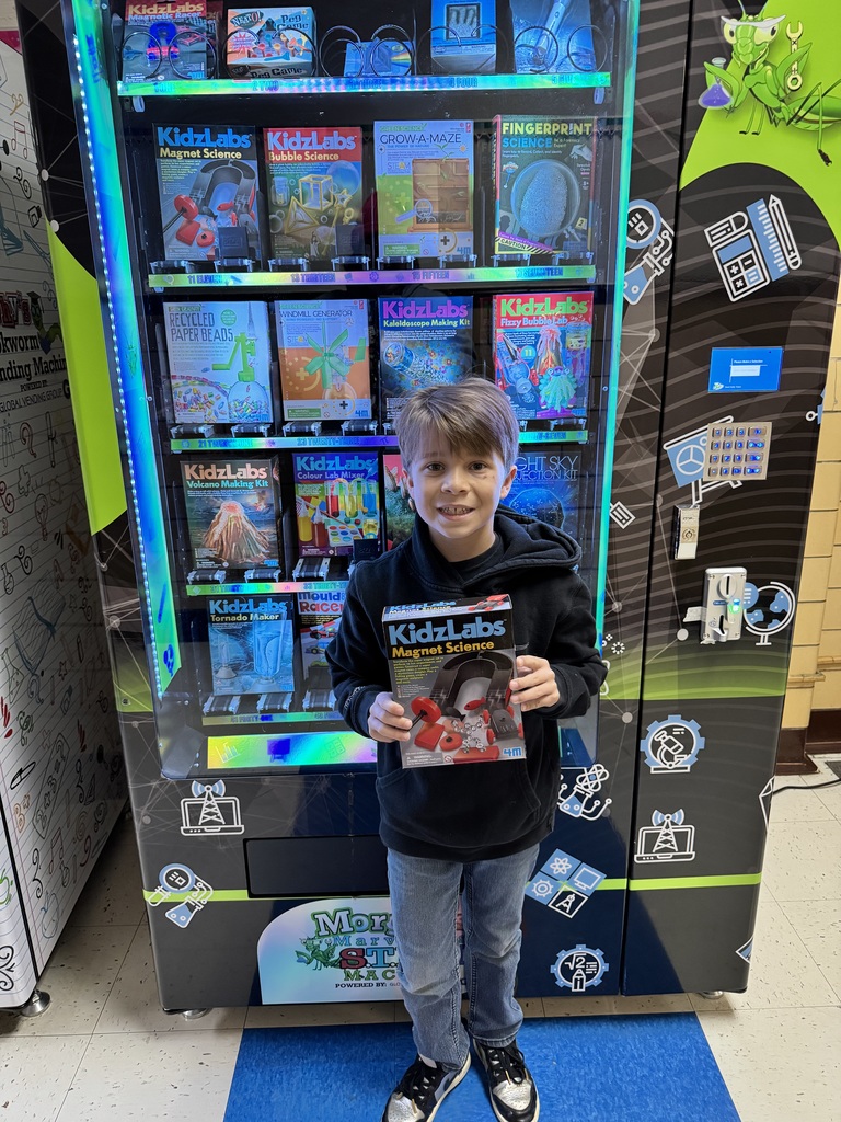Third grade student holds up a science kit he selected.