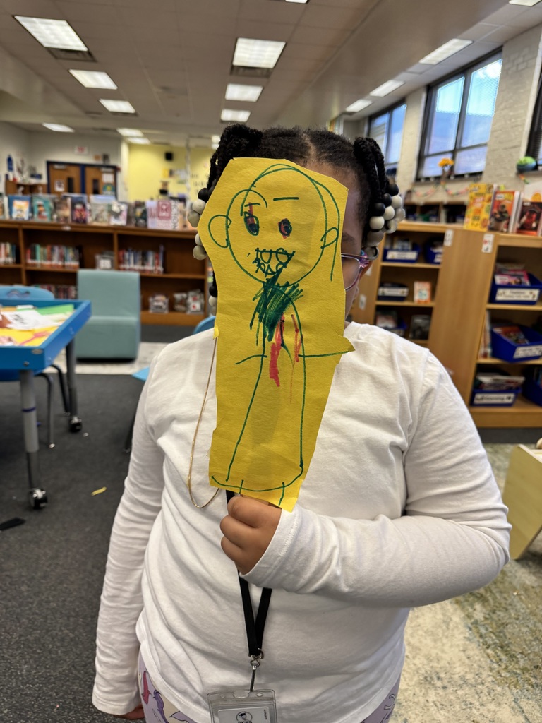 A student shows off their scary witch puppet.