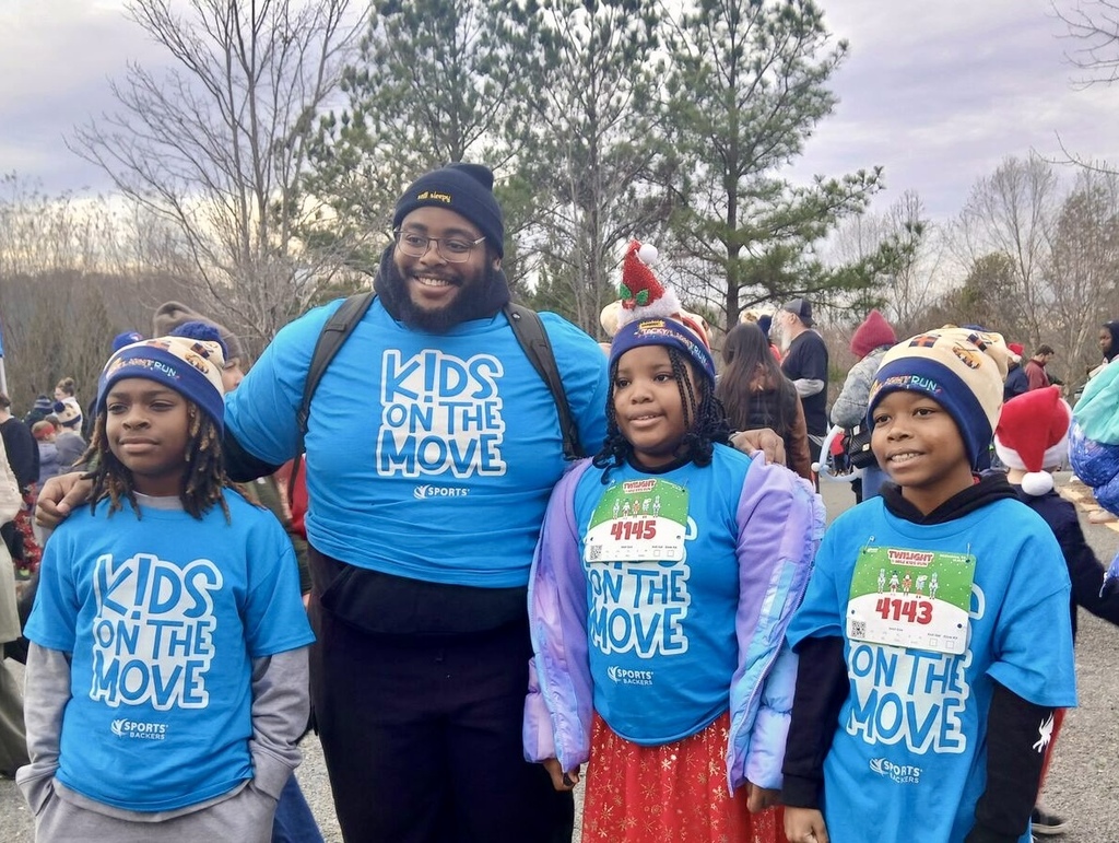 Three students stand with Coach Brown at the race.