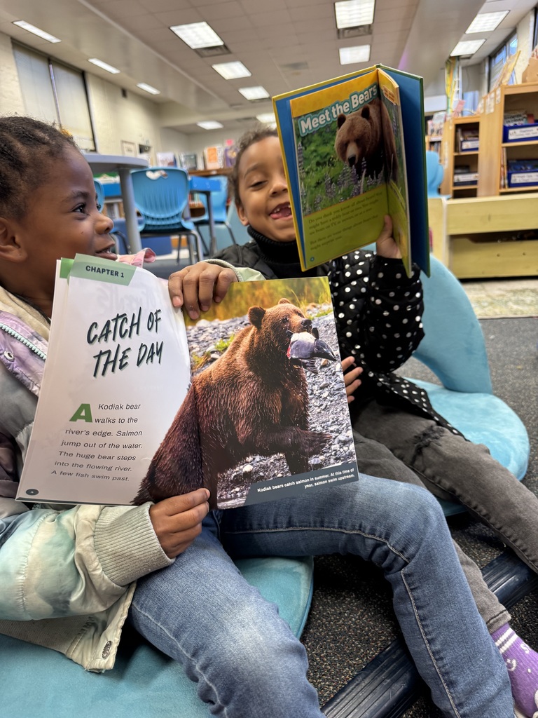 Two students show pictures they found in a bear book.