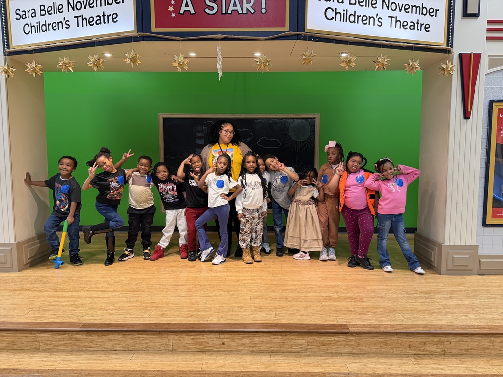 Students pose with their teacher on a stage.
