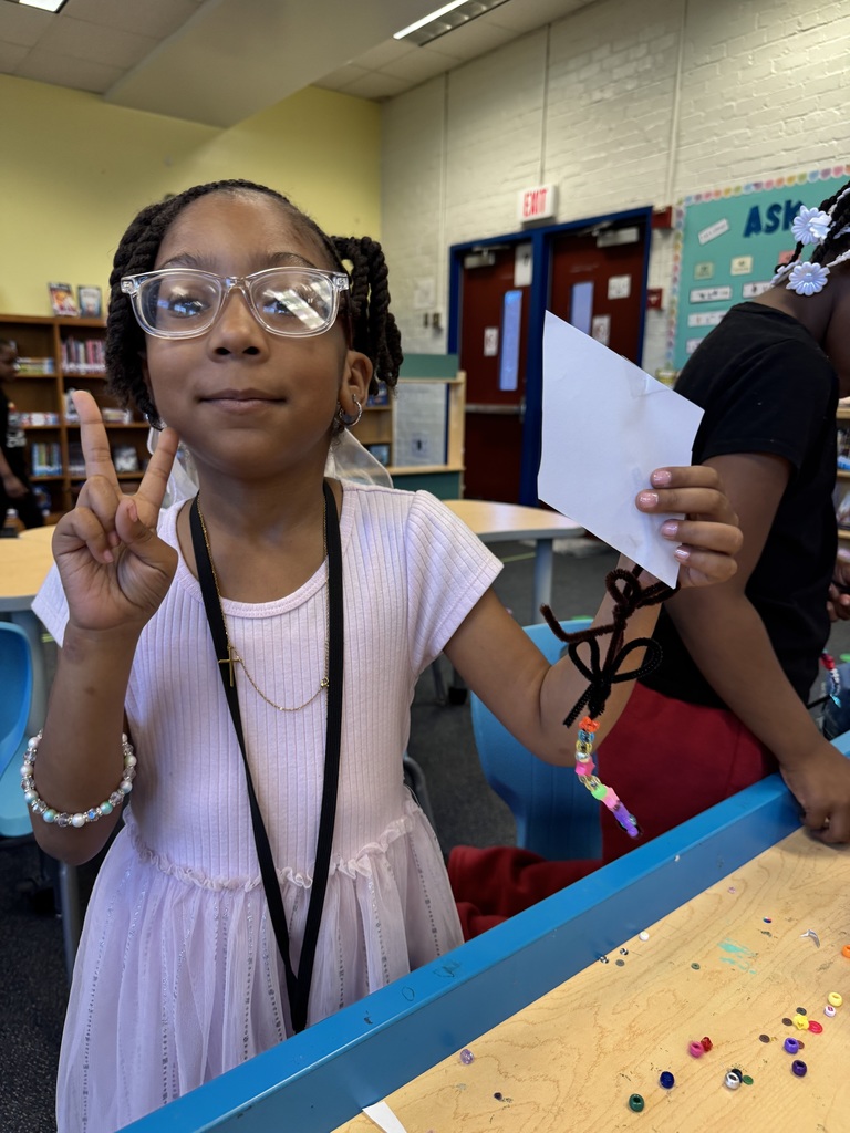Student holds up a paper kite that she made.