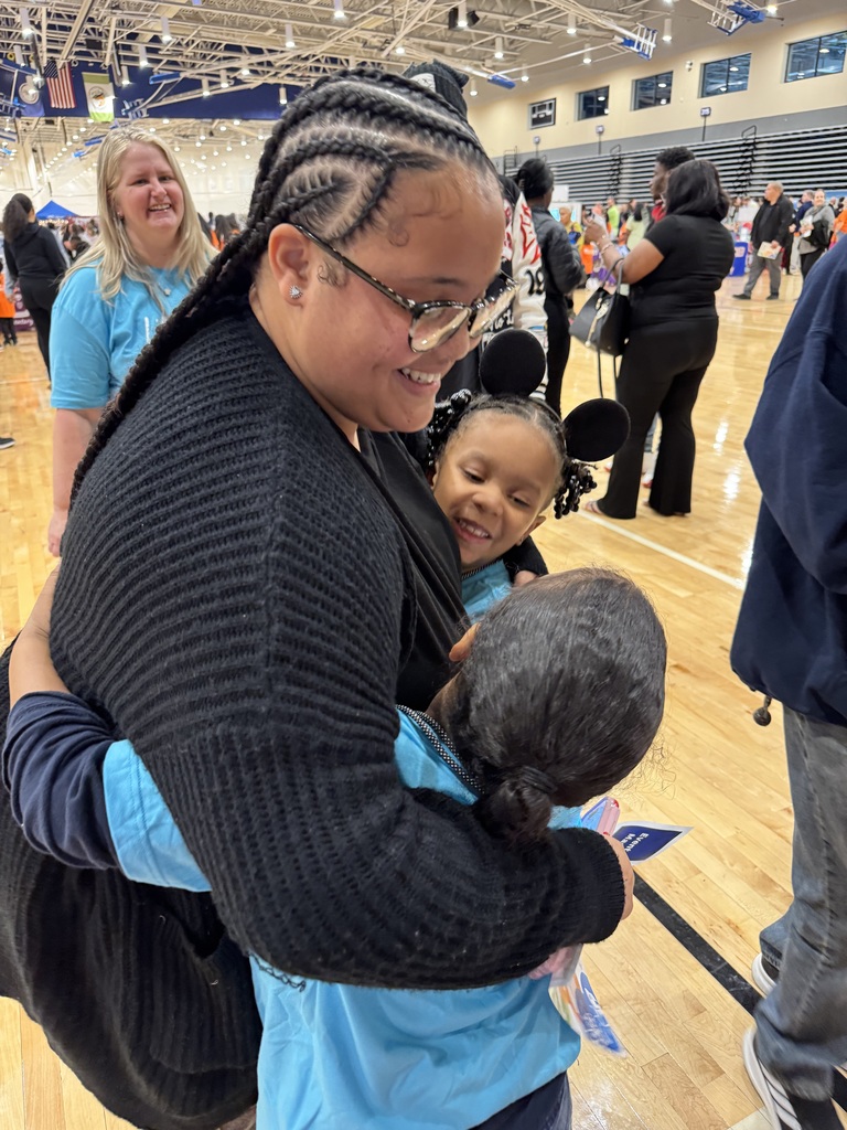 Teacher hugs her first grade students.