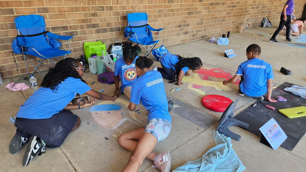 Students draw together on the sidewalk.