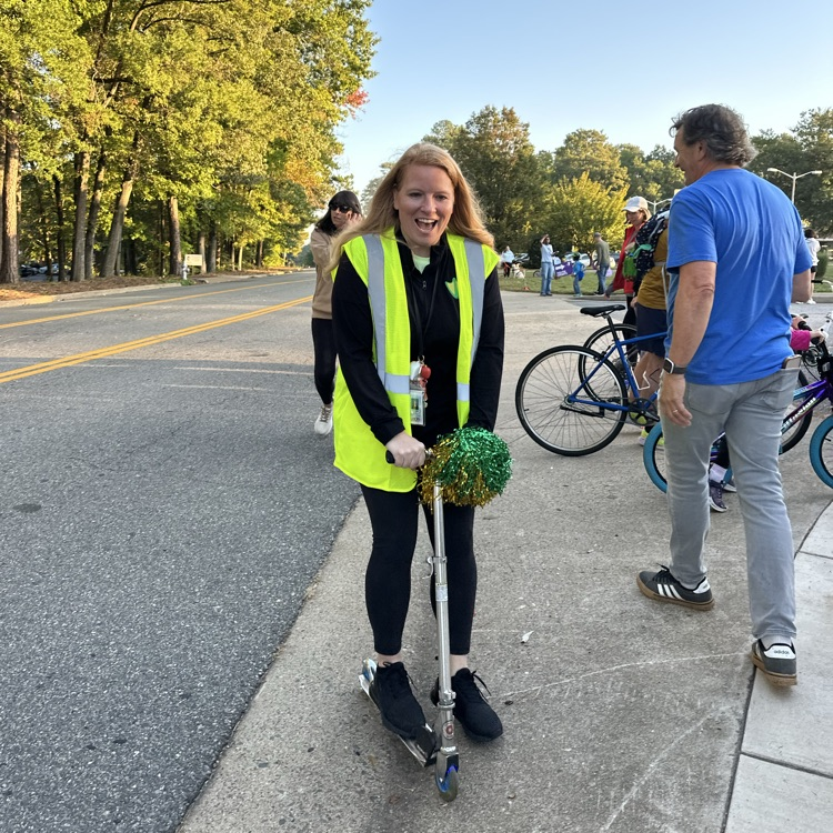 principal riding a scooter with a yellow vest on