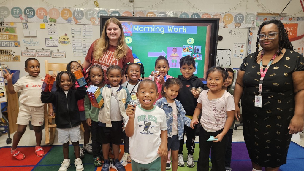 Ms. Mewborn stands on the carpet in her classroom with her students.
