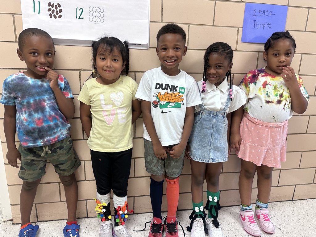 5 students stand in the hallway smiling.