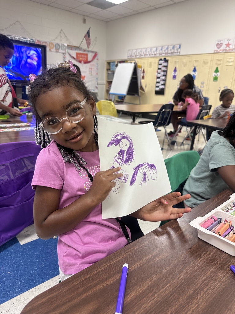Student holding up a purple drawing.