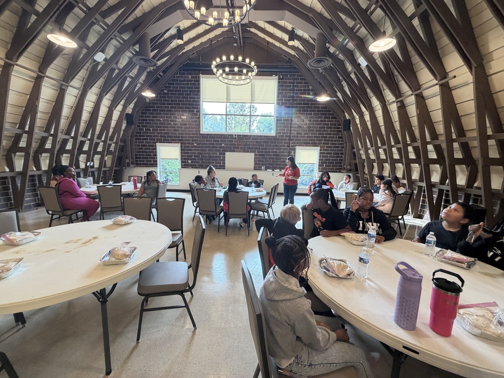 Students sit at tables with pans full of rice while an instuctor dicusses watersheds.