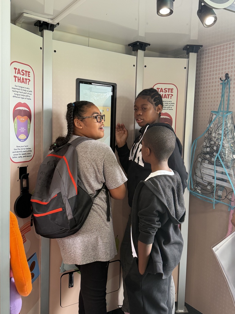 Three students stand infront of a science exhibit on taste.