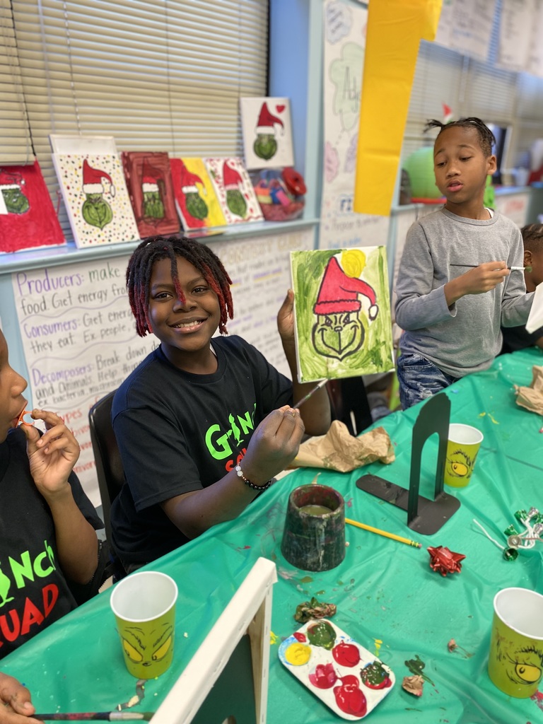 Fourth grade student shows their painting of the Grinch.