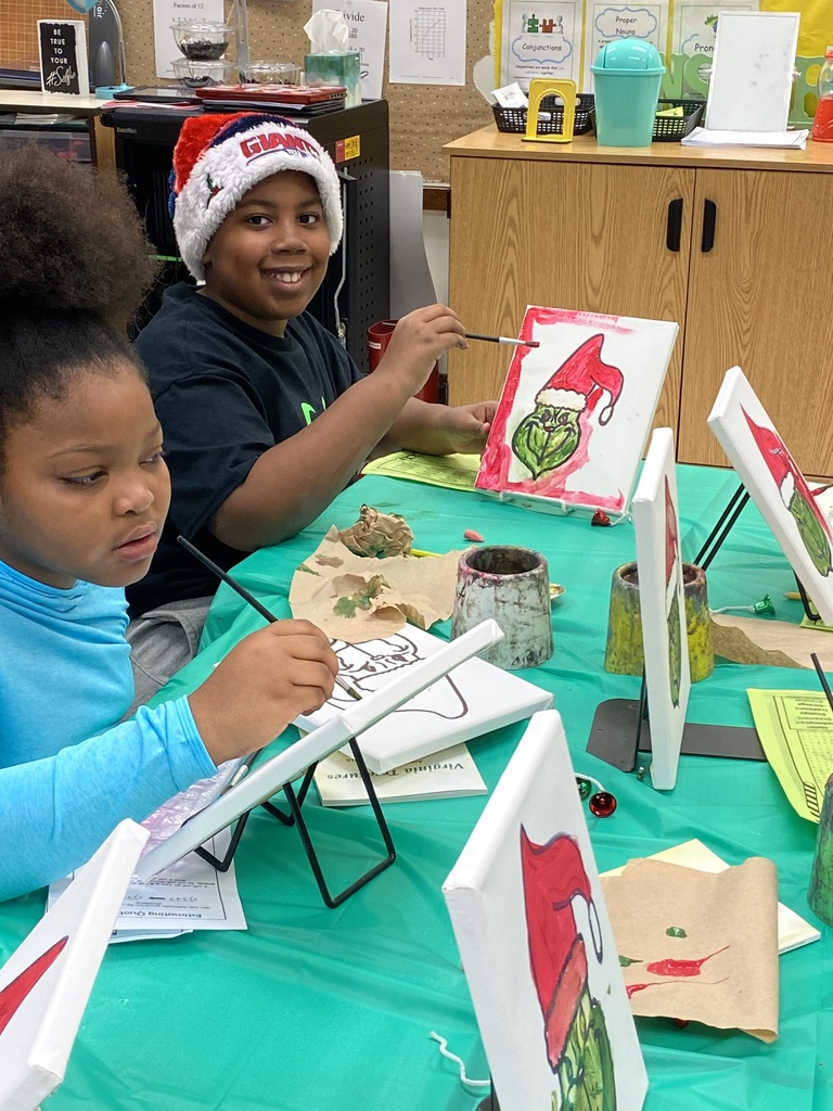 Fourth grade student shows their painting of the Grinch.