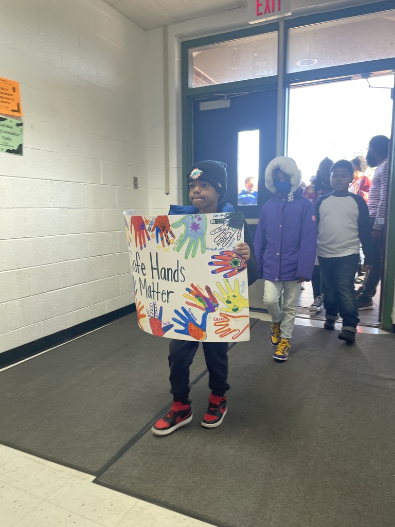 Student holds a poster that says "Safe Hands matter"