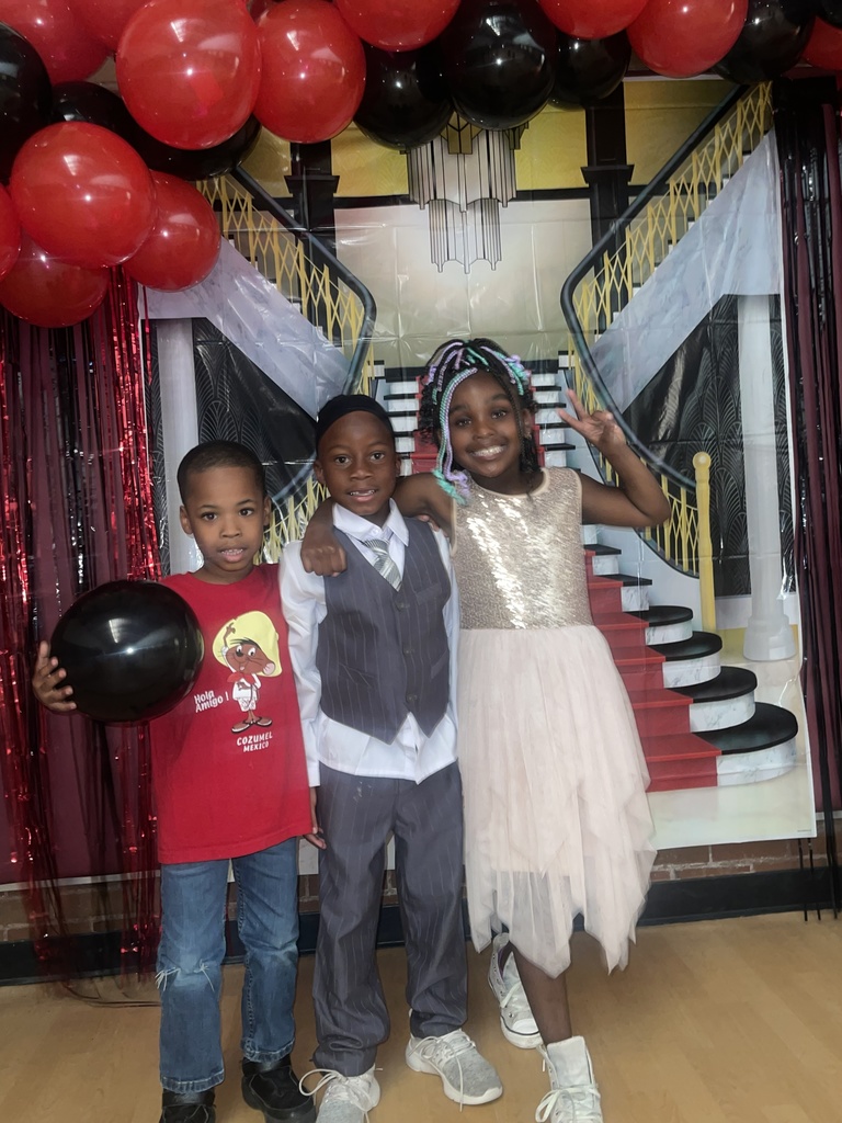 Three students smile with a peace sign in the air.