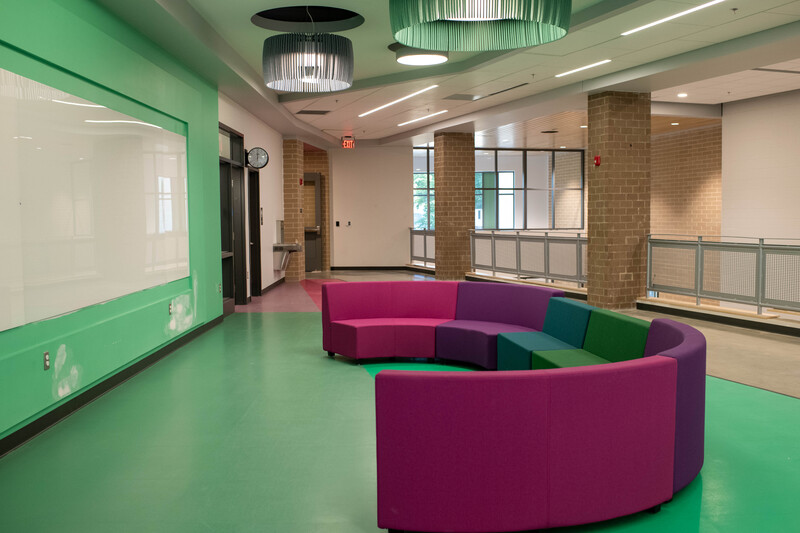 A lounge and learning space at the new R.C. Longan Elementary School. The floor and wall are green with a colorful couch set in the middle.