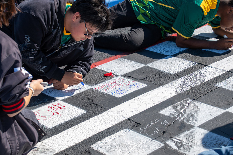 A student athlete from Henrico High School signs his name on the finish line on the track of Richmond Raceway after the competition.