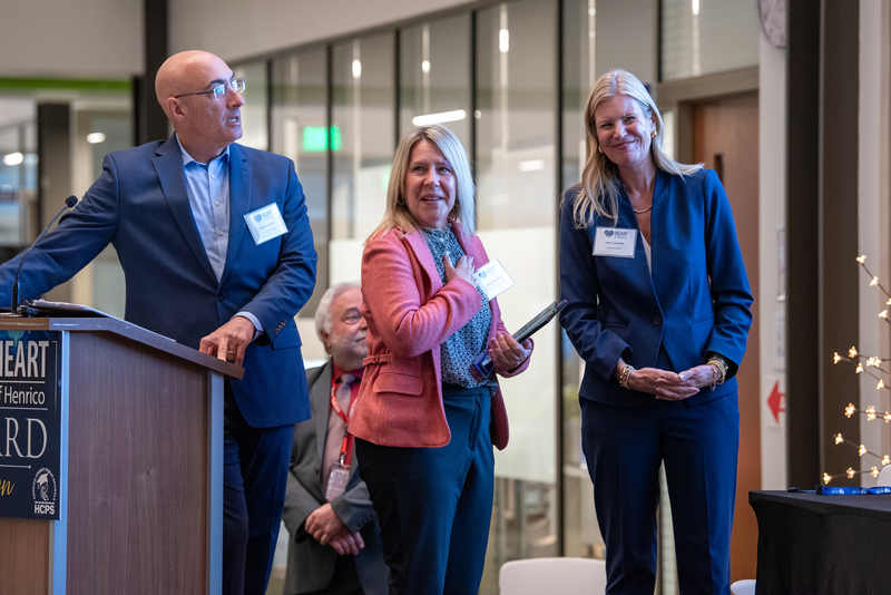 man at podium two women smiling