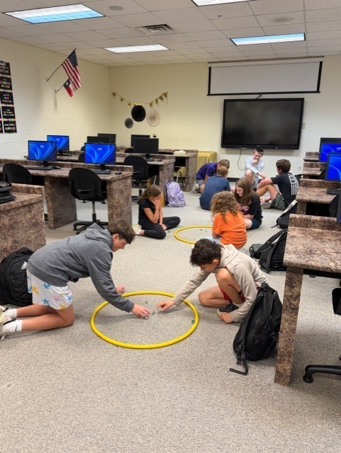 Students learning about the history of marbles and how to play!