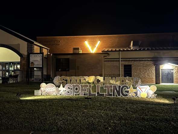 Building with lighted sign on front lawn reading "STATE CHAMPIONS SPELLING" in capital letters.